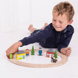 Child playing with a wooden toy train set on a white floor