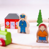 Wooden toy figures of a police officer and a child with a toy house and car in the background.